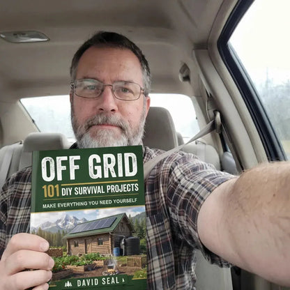 A reader holding the printed copy of Off Grid: 101 DIY Survival Projects in his car